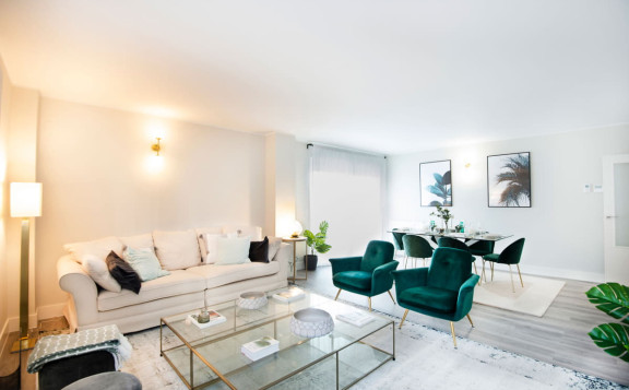 Salón con sofá, mesa auxiliar y butacas independientes de los pisos nuevos en Sabadell